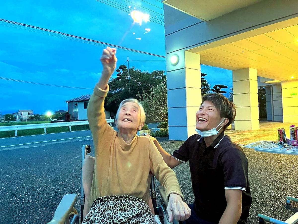 夏の夜、入居者様と職員がともに花火を見上げる様子